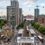 Canning Town skyline with modern apartment towers, train station, cable cars, and riverside homes in East London.