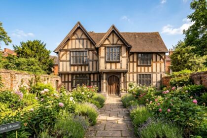 Exterior of Greyfriars House, a historic Tudor-style timber-framed building with a lush walled garden and stone path.