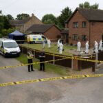 Forensic investigators and police officers examine a cordoned-off residential property in Wainfleet, with police tape, emergency vehicles, and evidence markers surrounding the house.