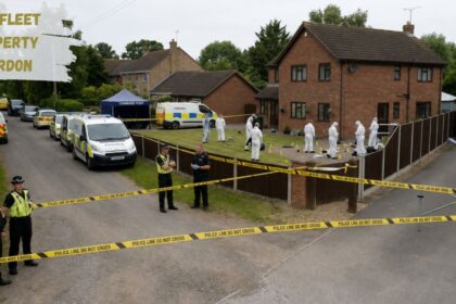 Forensic investigators and police officers examine a cordoned-off residential property in Wainfleet, with police tape, emergency vehicles, and evidence markers surrounding the house.