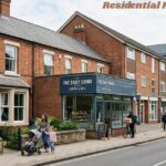 Residential property with red-brick homes, a café, pedestrians, and a street in a modern town setting.
