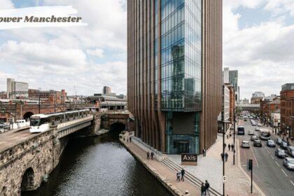 Axis Tower Manchester beside the canal and tram tracks, with city streets and historic brick buildings