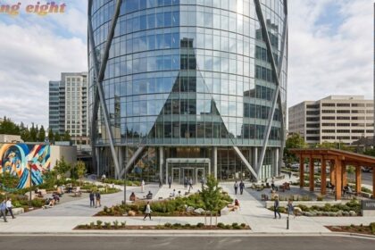 Building Eight modern glass office building with landscaped plaza and surrounding city buildings.
