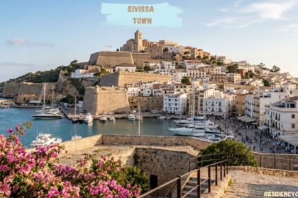 Eivissa Town historic hilltop buildings, stone fortress, harbor, and boats overlooking the Mediterranean Sea.